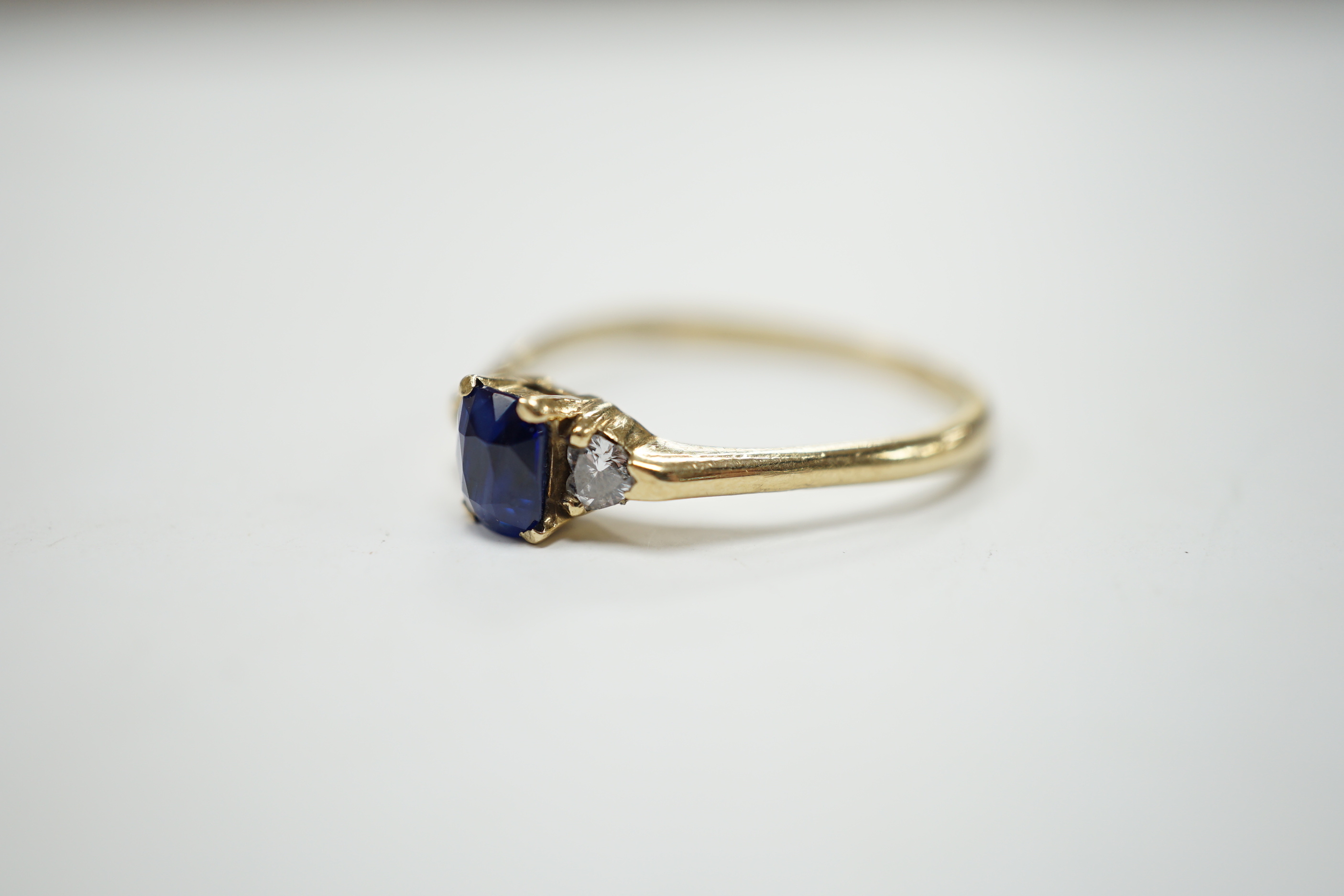 A yellow metal and single stone oval cut sapphire set ring, with two stone heart shaped diamond set shoulders, size U/V, gross weight 2.4 grams.